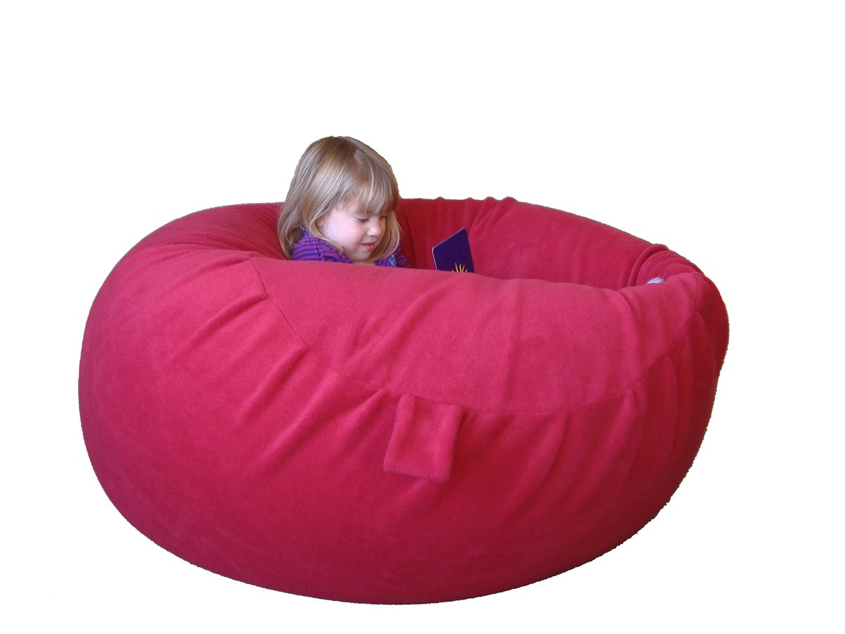 A child peering out of a large fire-engine-red fleece sensory beanbag