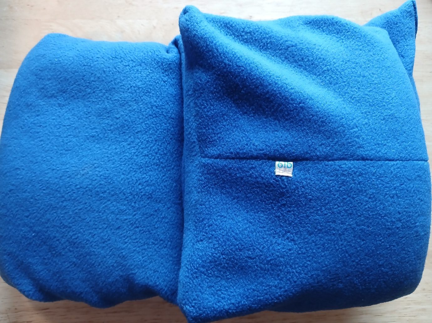 A royal blue fleece weighted lap pad, long and narrow, folded in half on a wooden table