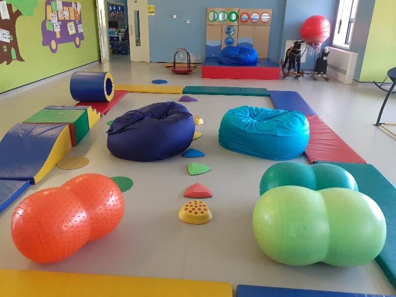 A school sensory room with X-Large lycra beanbags in turquoise, royal blue and navy among therapy balls, gym mats and stepping stones